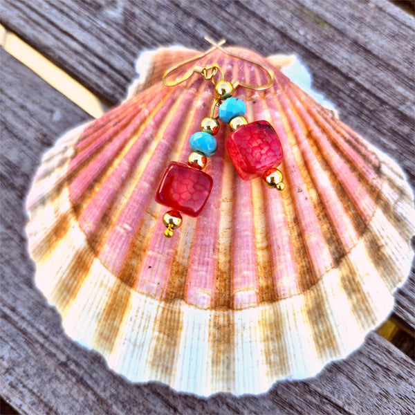 Colorful beaded earrings on a seashell with a wooden background