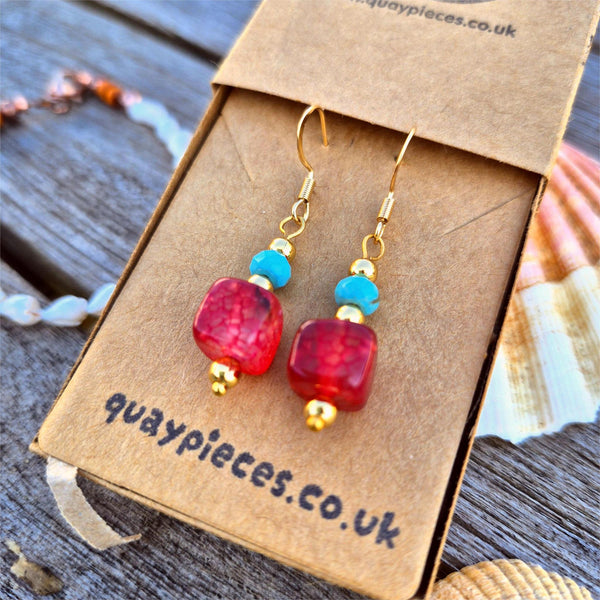 Red and blue beaded earrings on a brown card with 'quaypieces.co.uk' branding.