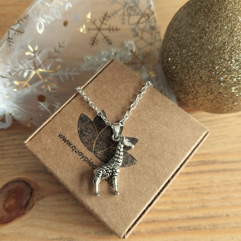 Silver giraffe necklace on a brown box with decorative background