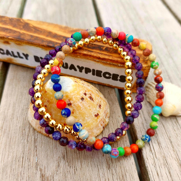 This stunning set of 3 handcrafted Beaded Bracelets features unique designs, including one with 4mm faceted purple stone beads, another with 4mm gold plated beads, and a third with 4mm mixed colour jasper beads. Each bracelet is elasticated for a comfortable fit on most adult wrists (7.5 in/19cm-they are designed to fit snugly) They make the perfect accessory for any summer outfit! Plus, they come in a lovely Kraft paper gift box with a reusable organza pouch.