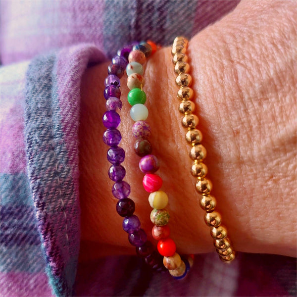 This stunning set of 3 handcrafted Beaded Bracelets features unique designs, including one with 4mm faceted purple stone beads, another with 4mm gold plated beads, and a third with 4mm mixed colour jasper beads. Each bracelet is elasticated for a comfortable fit on most adult wrists (7.5 in/19cm-they are designed to fit snugly) They make the perfect accessory for any summer outfit! Plus, they come in a lovely Kraft paper gift box with a reusable organza pouch.