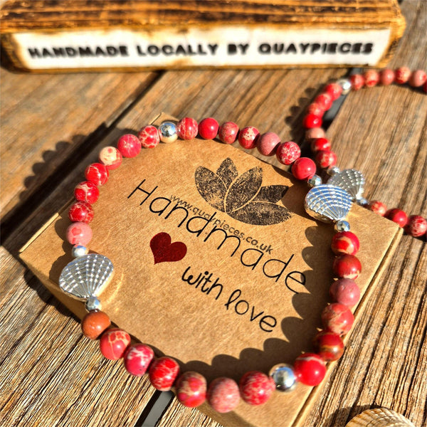 Beach vibes with this super cute stretch beach anklet, handmade with 6mm dark pink marbled imperial jasper stone beads &amp; silver plated shells plus hematite beads

Choose from sizes
M - elasticated at 23cm/9ins&nbsp;
or
L - elasticated at 25.4cm/10ins


Cool little gift for any surf chick!

**Presented in lovely Kraft paper gift box with reusable organza pouch**