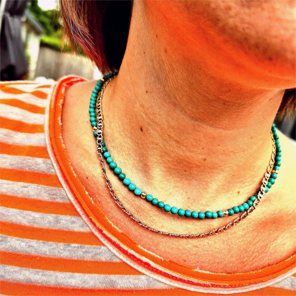 Close-up of a person wearing a turquoise beaded necklace with a blurred background
