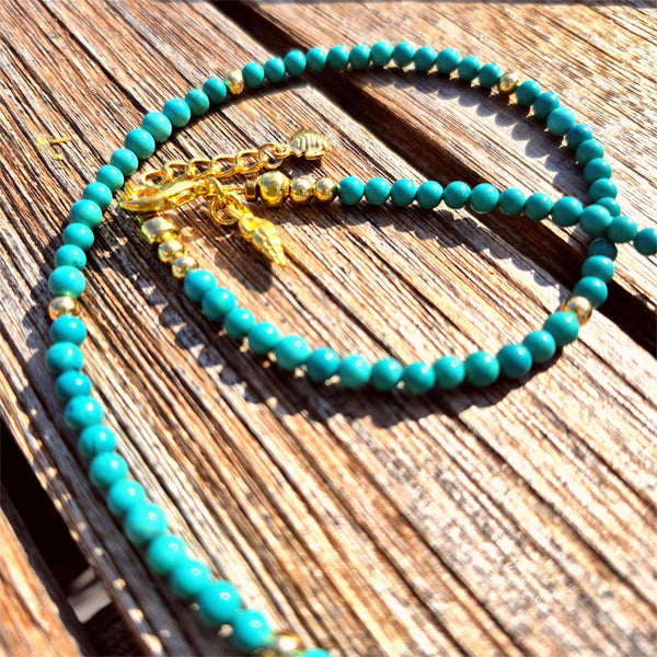Turquoise beaded necklace with gold accents on a wooden surface