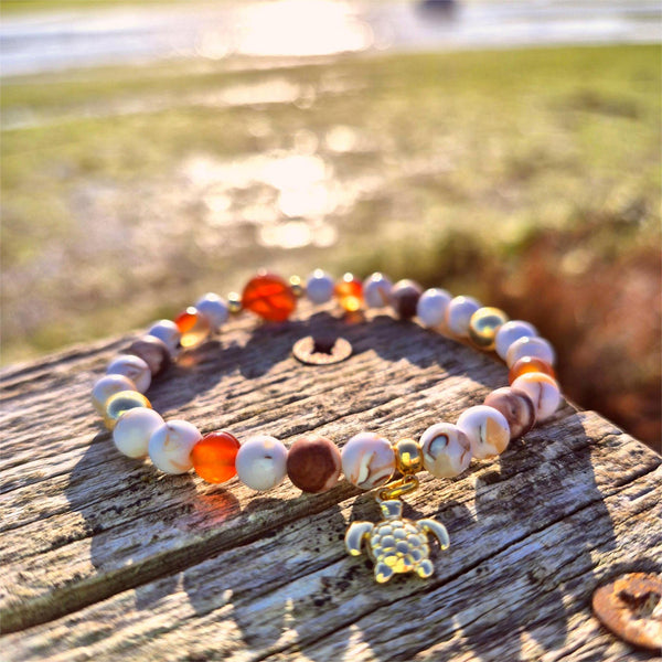 Colorful beaded bracelet with a turtle charm on a wooden surface outdoors