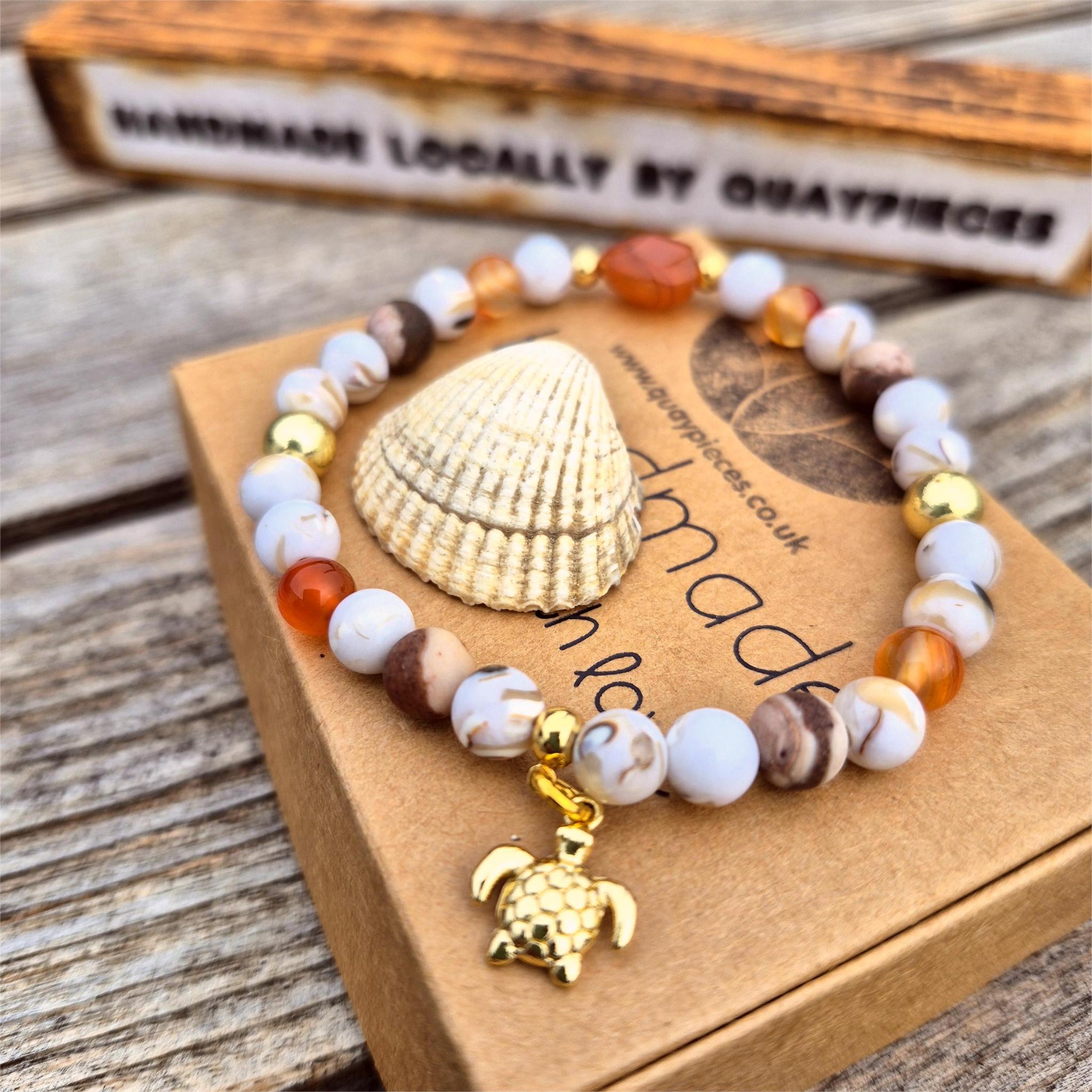 Beaded bracelet with a shell and turtle charm on a wooden surface