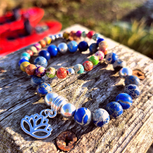 Colorful beaded bracelet with a silver lotus charm on a wooden surface