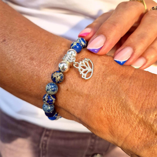 Bracelet with blue beads and a silver charm on a wrist.