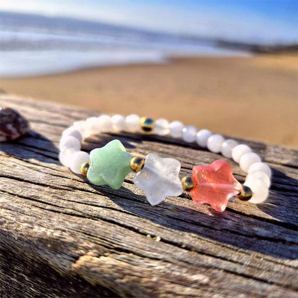 Star-shaped beaded bracelet on a wooden surface with a beach background