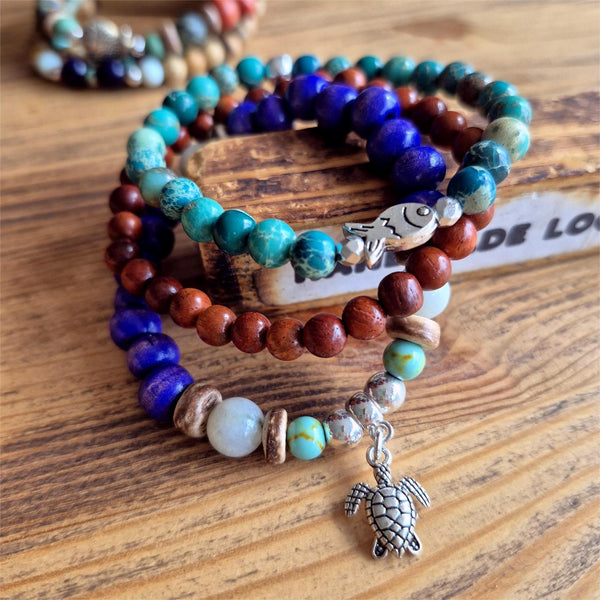Discover three stunning handmade bracelets that work beautifully together. This vibrant trio features 8mm purple wood beads with coconut discs, aqua stone beads &amp; silver turtle (nickel free), 6mm waxed natural wood beads paired with 6mm green imperial jasper beads with cute silver plated fish.