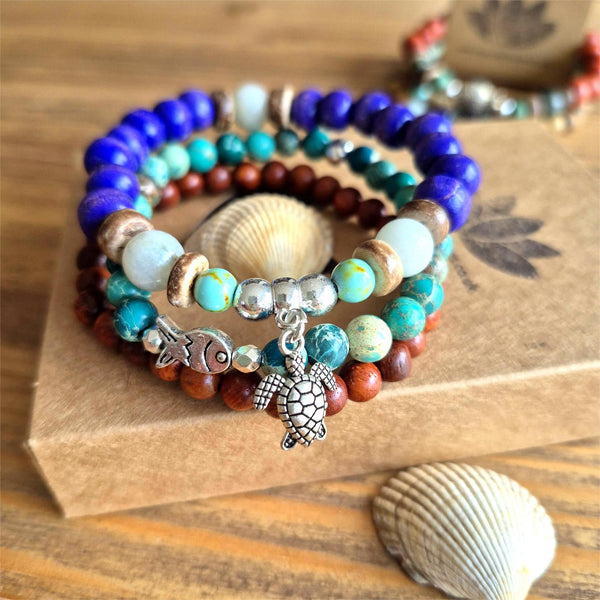 Discover three stunning handmade bracelets that work beautifully together. This vibrant trio features 8mm purple wood beads with coconut discs, aqua stone beads &amp; silver turtle (nickel free), 6mm waxed natural wood beads paired with 6mm green imperial jasper beads with cute silver plated fish.